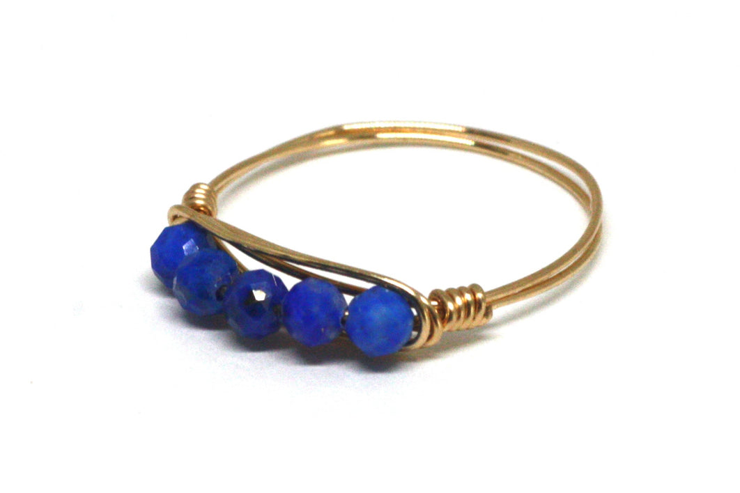 Gold ring with blue beads on a white background