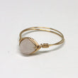 Gold ring with a round stone on a light gray background