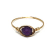 Gold ring with a purple gemstone on a white background
