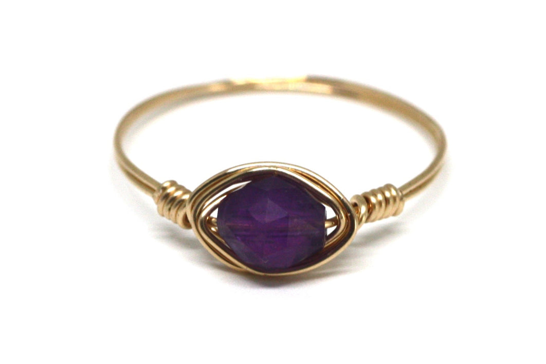 Gold ring with a purple gemstone on a white background